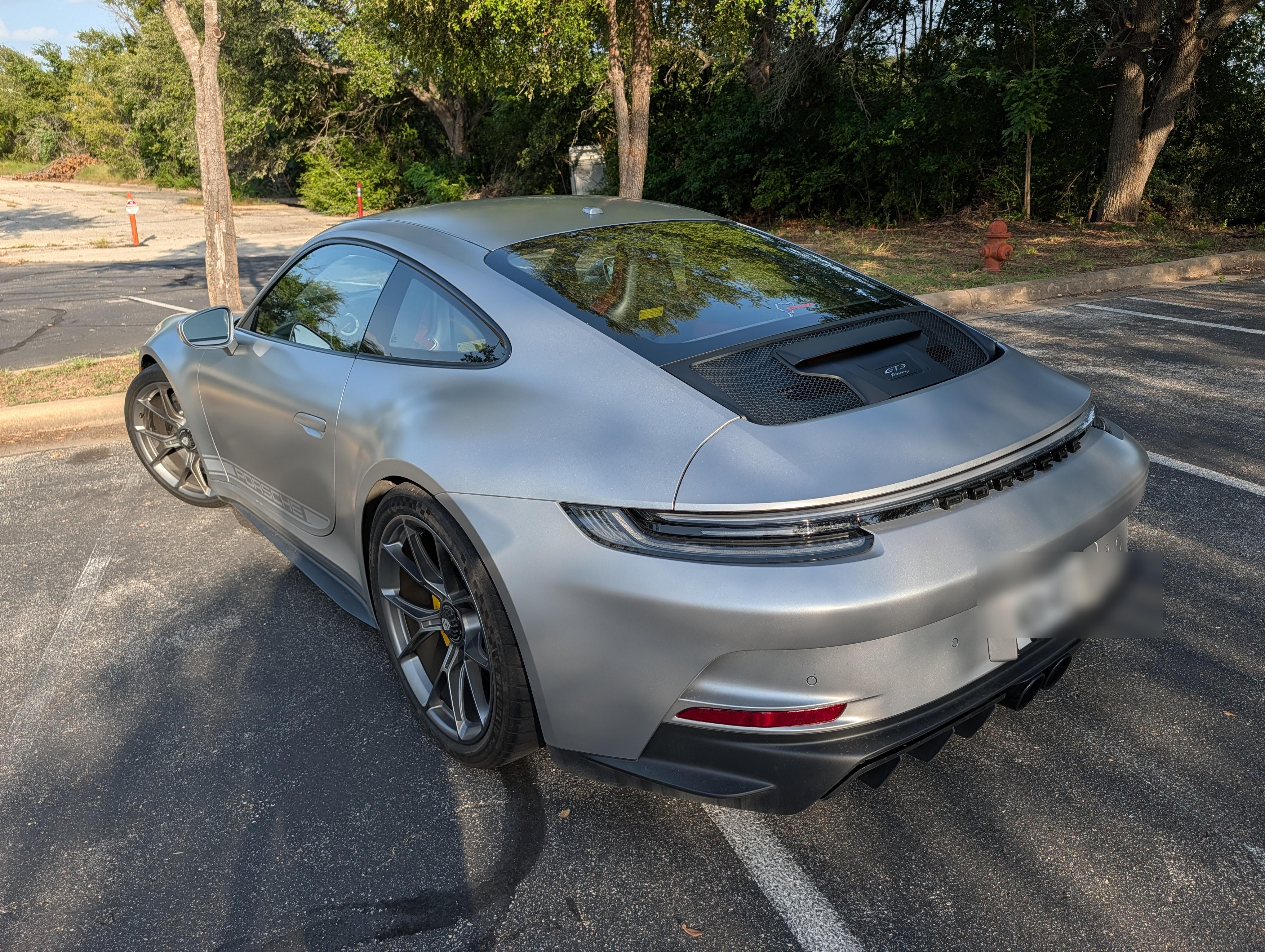 Rear three-quarter, tree-lined parking lot