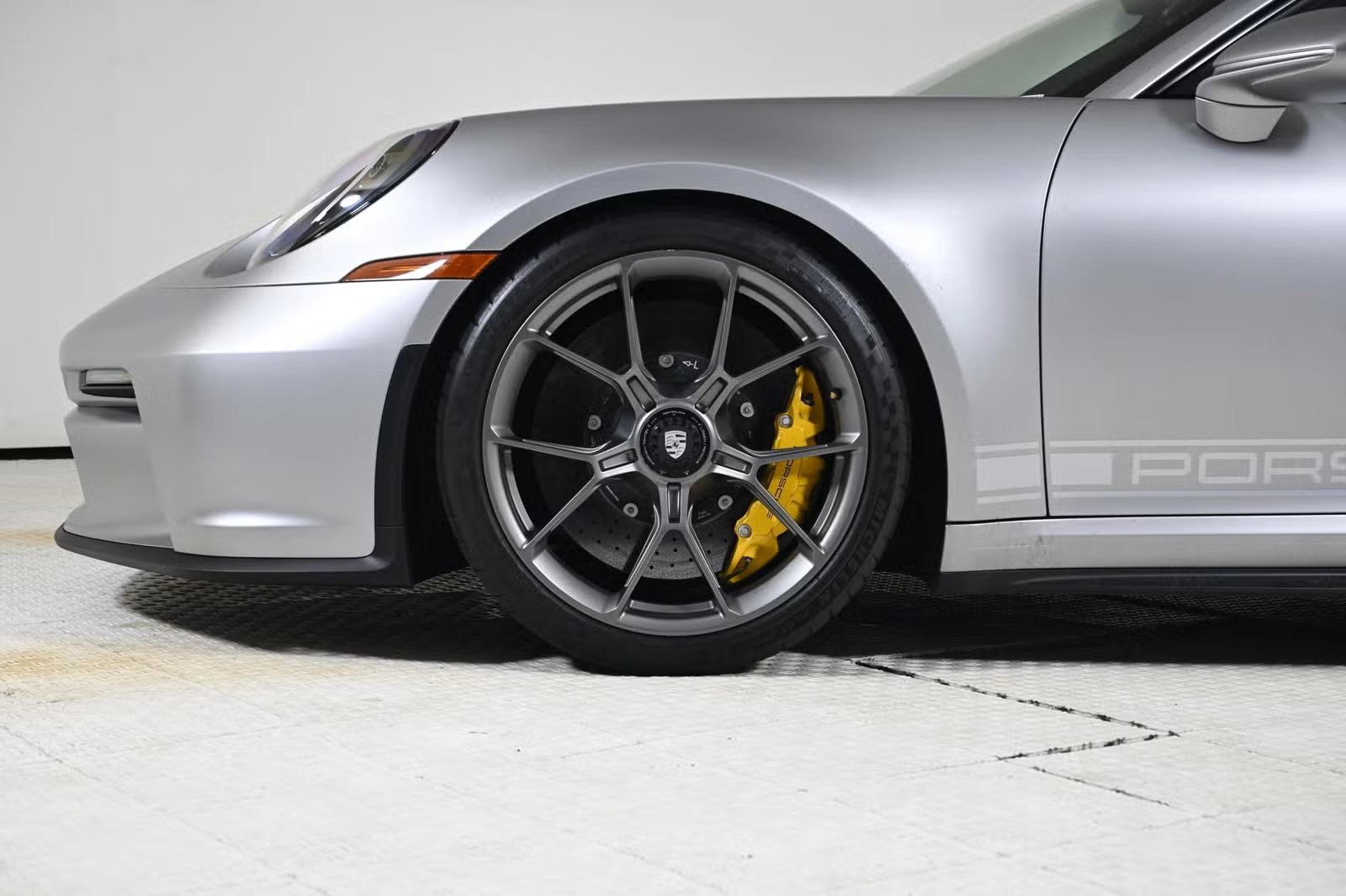 Wheel close-up showing Satin Dark Silver finish and yellow PCCB caliper